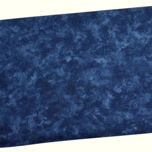 May include: A rectangular piece of fabric with a mottled pattern in shades of blue. The fabric has a textured appearance, with lighter blue areas contrasting against a darker blue background. The fabric is likely used for sewing or crafting projects.