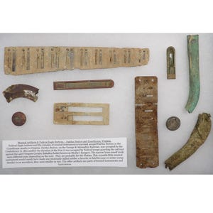 May include: A collection of antique musical artifacts and Federal Eagle buttons. The image shows various corroded metal pieces, including what appear to be parts of musical instruments and buttons. Text on a white card provides context.