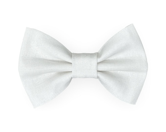 May include: A white bow tie made of textured fabric. The bow tie is centered and isolated on a white background. The bow tie has a classic shape with a central knot and symmetrical wings.