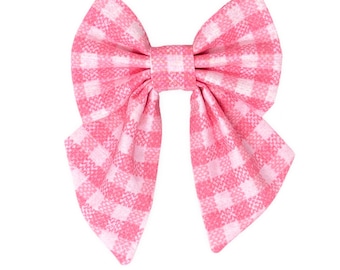 Op de afbeelding: Een roze en witte gingham strik met een grote, gecentreerde strik en twee lange, puntige uiteinden.