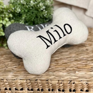 Cream and Grey bone shaped squeaky toys for a dog sitting on a wicker basket