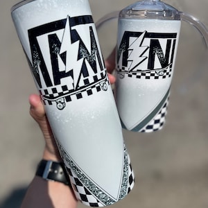 May include: Two white tumblers with a black and white design. The design includes the letters "FN" with a lightning bolt and a skateboard. One tumbler has a lid and a handle. The other tumbler is a standard size.