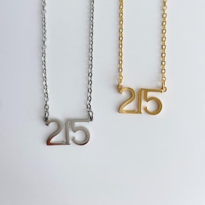 May include: Two necklaces with the number 215 on them. One necklace is silver and the other is gold.