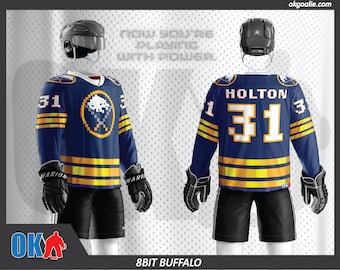 May include: A blue and gold hockey jersey with a pixelated buffalo logo and the number 31 on the front. The jersey has the text "HOLTON" on the back. The jersey is worn by a hockey player with a black helmet and gloves.