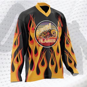 May include: Black hockey jersey with a yellow and red flame pattern. The jersey has a circular logo with the text "Flavortown Flames" and a cartoon image of a man with a mustache.