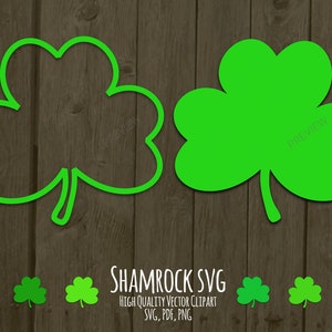 May include: Two shamrock designs, one filled in green and the other an outline in green. The designs are on a woodgrain background. The text "SHAMROCK SVG" is below the designs.