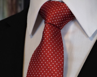 May include: A red tie with white polka dots. The tie is made of a silky material and has a classic design.
