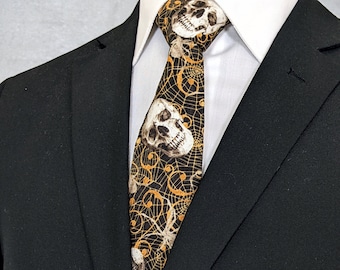 May include: A black suit jacket with a black and gold tie featuring a skull and spiderweb pattern.