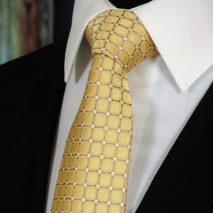 May include: A gold tie with a geometric pattern. The tie is made of a silky fabric and has a classic design.