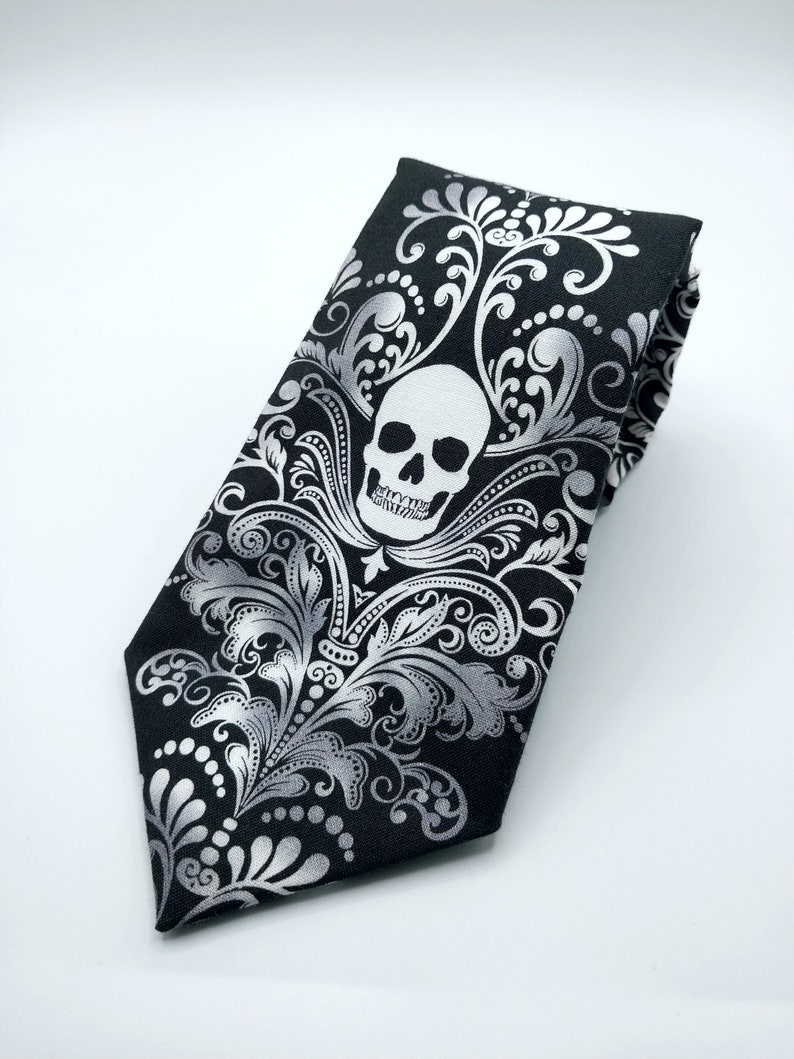 May include: A black tie with a silver skull and floral pattern.
