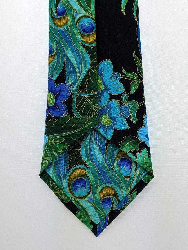 May include: A black necktie with a peacock feather and floral pattern in shades of blue, green, and gold.