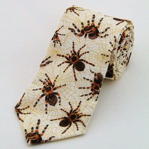 May include: A white tie with a pattern of brown and orange spiders and webs.