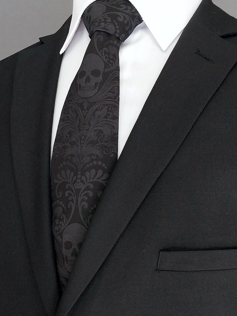 May include: A black suit with a black and white skull patterned tie. The tie has a paisley design.