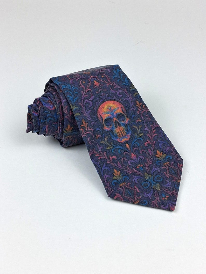 May include: A rolled-up necktie with a dark blue background and a colorful skull design. The skull is orange, yellow, and blue. The tie has a floral pattern in shades of blue, purple, and orange.
