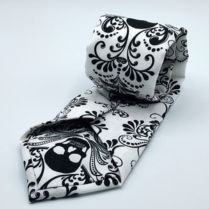May include: A white tie with a black skull and floral pattern.