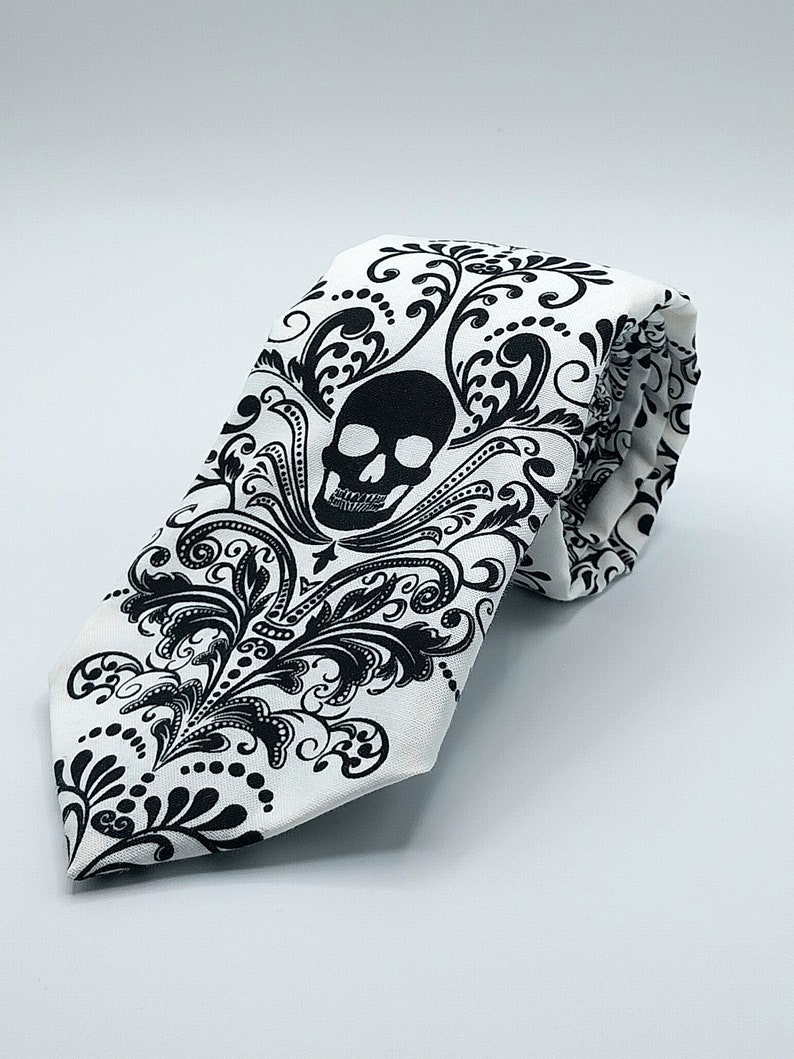 May include: A white tie with a black skull and floral pattern.