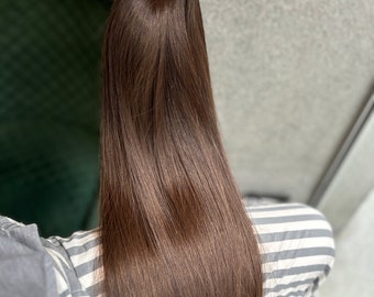 以下が含まれることがあります： 上部にウェフトクリップが付いた、長くストレートな茶色のヒューマンヘアエクステンション
