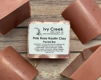 May include: Four pink rose kaolin clay facial bars, each in a half-circle shape, with one bar showing the label: "Ivy Creek Harris County, GA www.IvyCreekGardens.com Pink Rose Kaolin Clay Facial Bar Ingredients: Coconut Oil, Palm Oil, Safflower Oil. Kosher Vegetable Glycerin, Shea Butter, Purified Water, Sodium Hydroxide, Sorbitol, Sorbitan oleate, Oat protein, Titanium Dioxide. Jojoba Oil, Chamomile Extract, Rose Clay 1 bar (4.2 oz)"