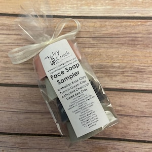 May include: A sampler pack of four face soaps in a clear plastic bag tied with a white ribbon. The soaps are labeled with the names of the clays used: Australian Rose Clay, French Green Clay, Activated Charcoal, and Dead Sea Clay. The bag also includes the text "Ivy Creek Face Soap Sampler".