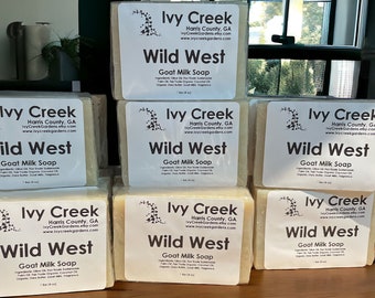 May include: A stack of six bars of goat milk soap with the label "Ivy Creek Wild West Goat Milk Soap" in white text on a white background. The soap is packaged in clear plastic wrap.