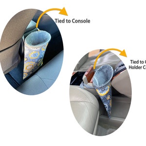 May include: A gray and yellow floral patterned fabric car trash can with a drawstring top. The trash can is tied to the center console of a car. The trash can is also tied to a cup holder cover in a car.
