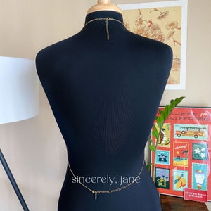 The back of a body chain on a mannequin with chain around the waist and neck