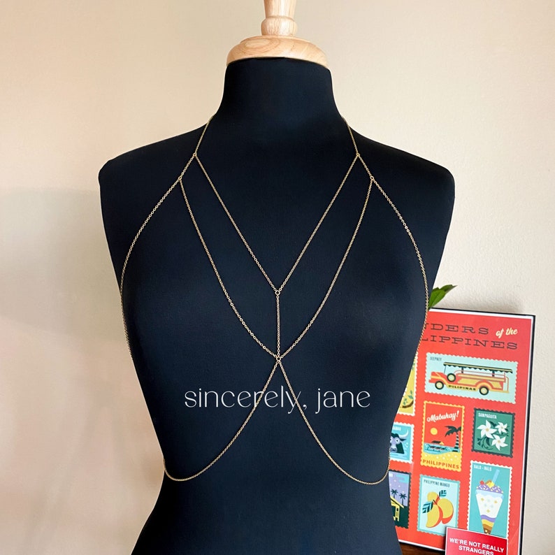 A body chain displayed on a mannequin, set against a wall adorned with Filipino artwork