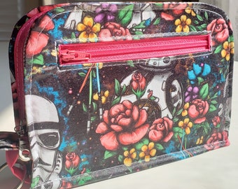 Può includere: Una pochette nera con cerniera con una stampa floreale e spaziale colorata. La stampa presenta rose, stelle e un personaggio di Star Wars.
