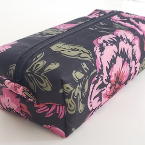 May include: Black zippered pouch with a floral print featuring pink and green flowers.