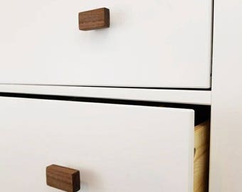 May include: White dresser with two drawers and wooden knobs. The bottom drawer is open, revealing a wooden interior.