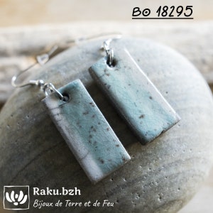Puede incluir: Un par de pendientes de plata con colgantes rectangulares de cerámica azul y blanca. Los colgantes tienen un esmalte craquelado y un patrón moteado. Los pendientes están etiquetados como "BO 18295".