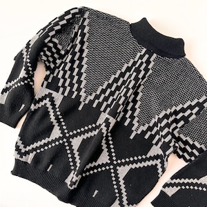 May include: Black and white geometric patterned sweater with a mock neck.