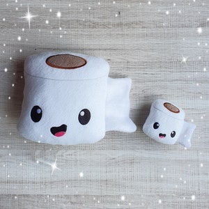 May include: Two plush white toilet paper rolls with smiling faces. The larger roll has a brown paper core and the smaller roll has a brown paper core.
