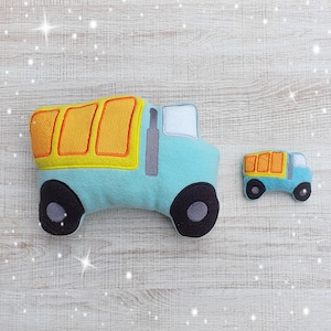 May include: Two plush toy dump trucks. The larger truck is blue with yellow and orange details. The smaller truck is blue with orange details. Both trucks are on a light wood background.