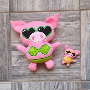 May include: Two pink plush pig toys wearing sunglasses and swimsuits. The larger pig has a green bow and the smaller pig has a yellow bow.