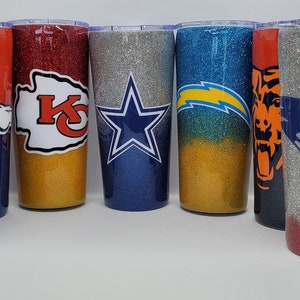 May include: Eight different glitter tumblers with various NFL team logos. The tumblers are all the same size and shape, and they are all made of stainless steel. The logos are all printed on the front of the tumblers, and they are all in different colors.