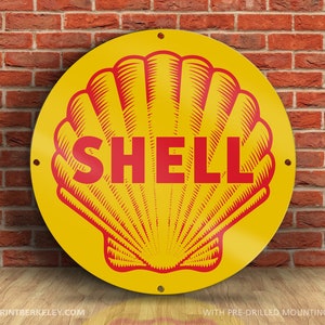 May include: A round, yellow Shell sign with a red seashell design and the word "SHELL" in red. The sign is against a brick wall and has pre-drilled mounting holes. The sign is a vintage style advertisement.