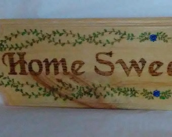 Home Sweet Home wood burned sign with vines and leaves and small blue flowers  painted and embellished with colored crystals