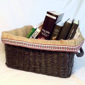 May include: A brown wicker basket with a burlap liner and red and white trim, filled with a stack of books. The books have titles in Russian and English, including "Shadow of the Mountains" and "The Science of the Flat Earth".