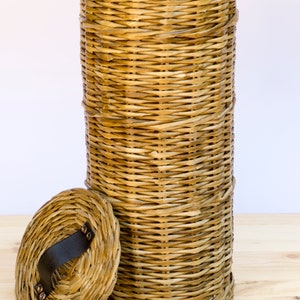 May include: A woven wicker storage basket with a lid. The lid has a black leather handle and metal accents.