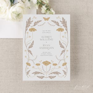 May include: Save the date card with a floral design in shades of brown and gold. The card features the text "Save the date for the wedding of Audrey Williams & Ryan Anderson" with the date "July 22, 2025" and location "Los Angeles, California".