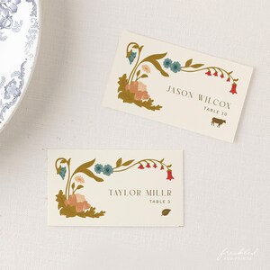 May include: Two floral place cards with gold, red, and blue accents. The top card reads "Jason Wilcox, Table 10" and the bottom card reads "Taylor Miller, Table 3".