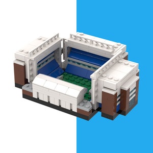 May include: A white and brown Lego model of a football stadium with blue seats and a green pitch.
