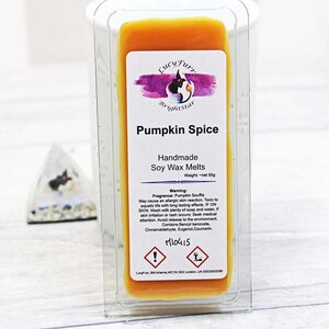 May include: A clear plastic container with a yellow soy wax melt inside. The label reads "Pumpkin Spice Handmade Soy Wax Melts" with a warning about potential allergic reactions. The label also includes the text "Weight - net 50g".