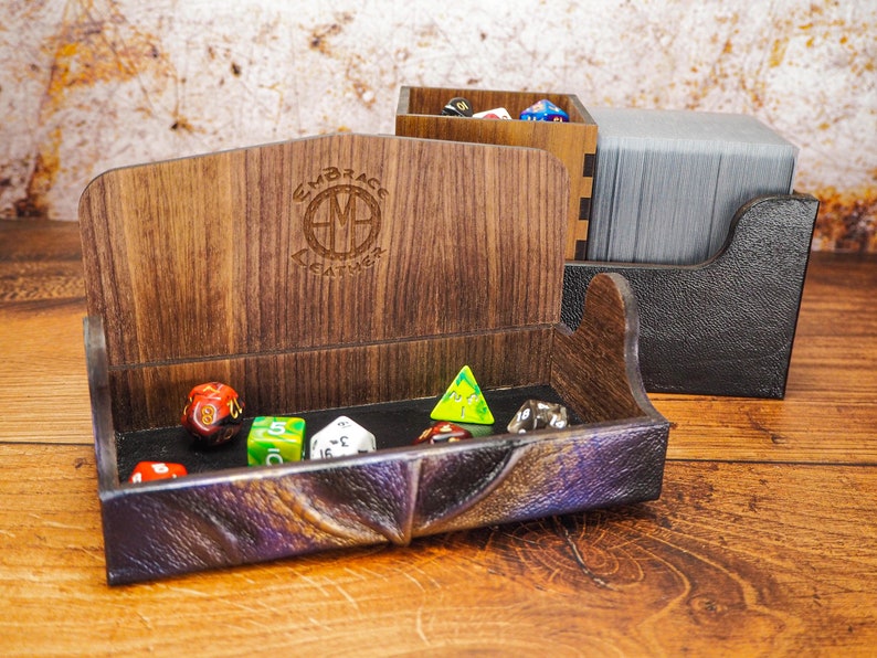 May include: A wooden dice tray with a leather-like lining and a compartment for cards. The tray is filled with colorful dice and has the text "Embrace the Adventure" engraved on the side.