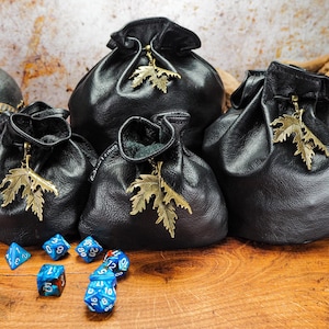 Schwarze Leder-Würfeltasche mit einem bronzefarbenen Ahornblatt und optionaler Gürtelschlaufe