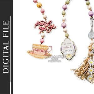 May include: Three wooden bead garlands with different charms. The first garland has a pink teacup and saucer, the second has a sign that says "100% Natural Herbal Tea from teacup", and the third has a silver spoon and a burlap tassel with white daisies.