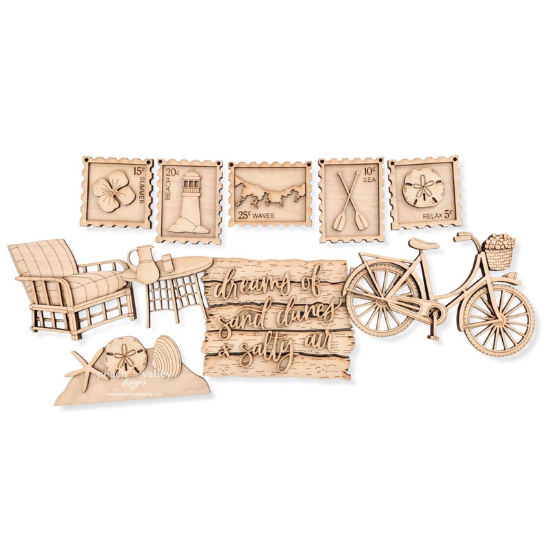 May include: Wooden cutout decorations with a beach theme. The set includes a beach chair, a table, a starfish, a seashell, a bicycle, a sign that says "dreams of sand dunes & salty air", and five postage stamp-shaped cutouts with beach-themed images and text.