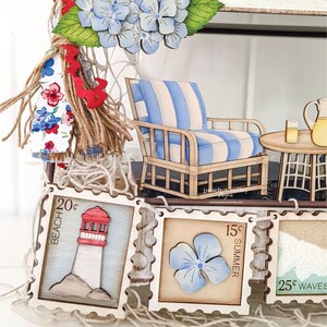 May include: A wooden banner with five decorative stamps featuring a lighthouse, a flower, and the words "Beach 20c", "Summer 15c", and "Waves 25c".
