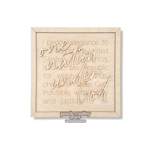 May include: A wooden sign with the text "I pledge allegiance to the flag of the United States of America, and to the Republic for which it stands, one nation under God, indivisible, with liberty and justice for all." The sign is framed in wood and has a light wood finish.
